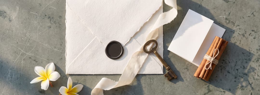A sealed envelope, a brass key on a silk ribbon and a bundle of Ceylon cinnamon, laid out on stone in first light