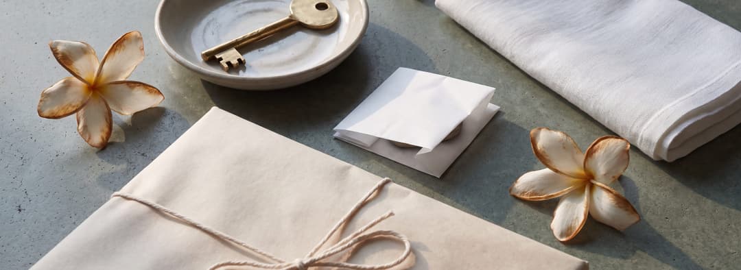 A wrapped parcel, a returned brass key on a ceramic dish and frangipani a day past their best, under silver light